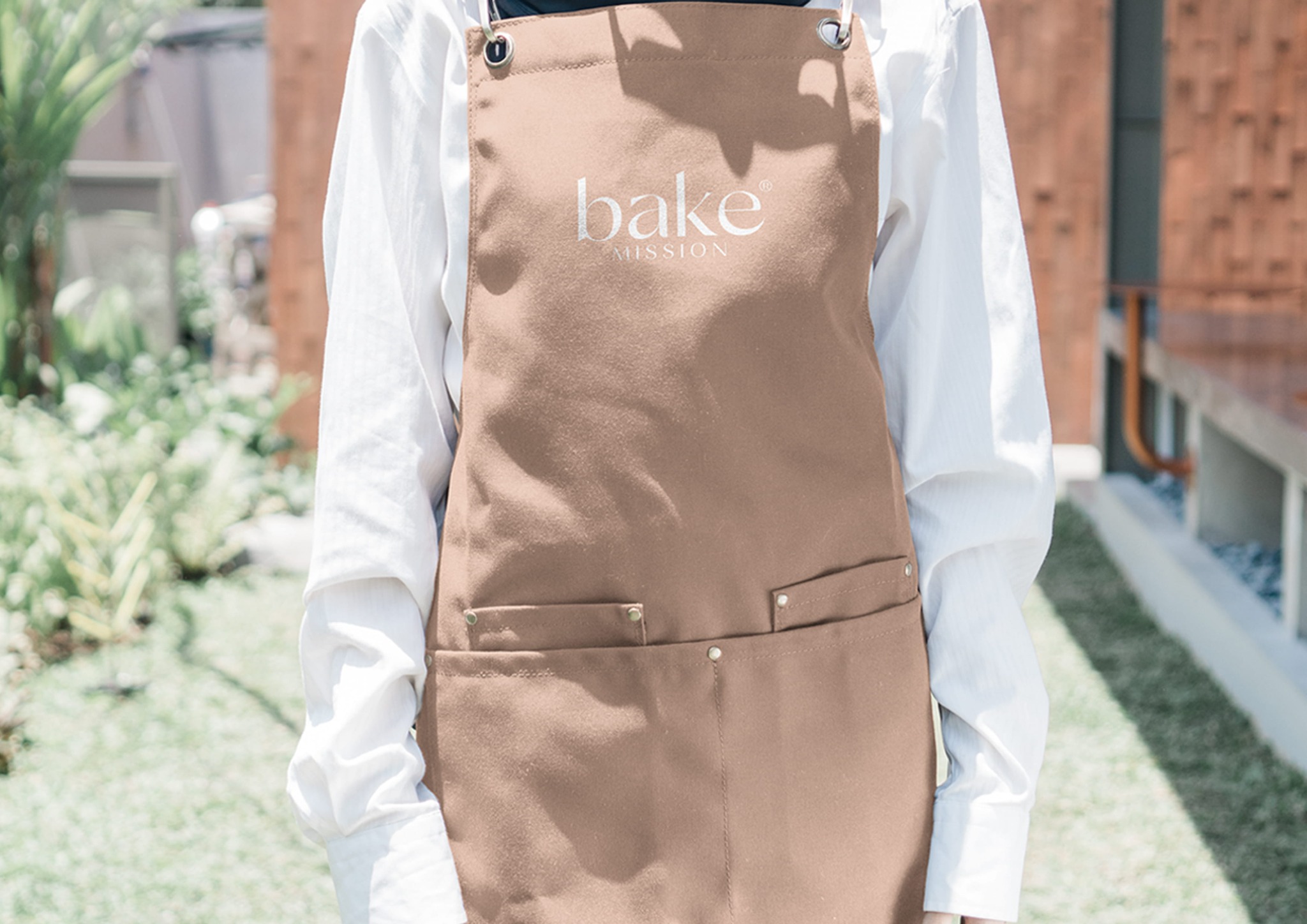 Bake Mission hospitality branding embroidered on a warm neutral apron